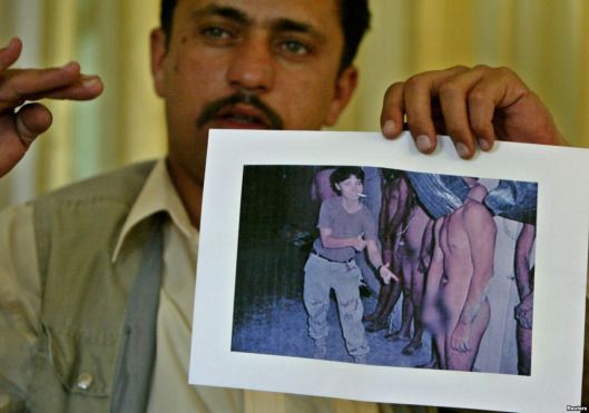 A former prisoner at Abu Ghraib shows a photograph, now infamous, of abuse at the prison. Photo via Reuters