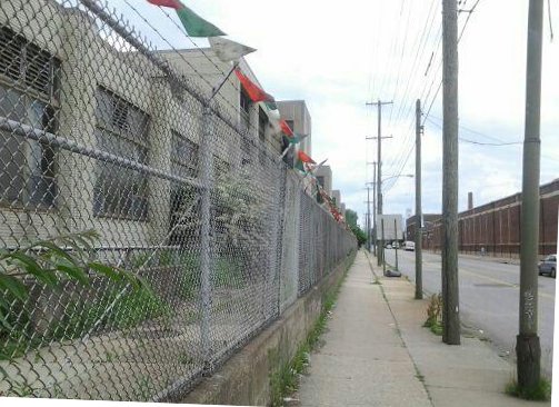 The 20th Street side of the DVIC has the appearance of an abandoned used car dealer, though some signs of activity can be detected within via fluorescent light peeking through papered windows. Photo by Kenneth Lipp
