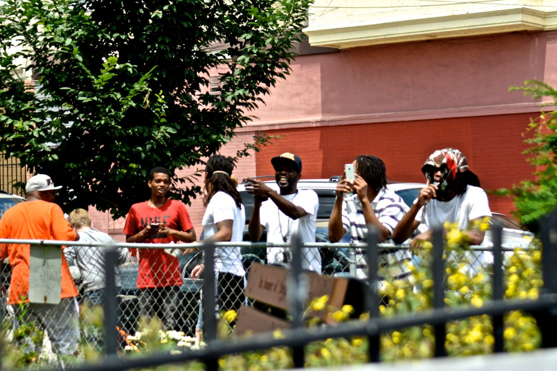 Members of the neighborhood watch and take pictures of the rally. Photo by Joshua Albert