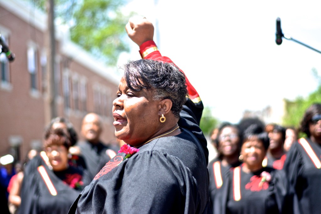 A local choir begins singing as the home is demolished.