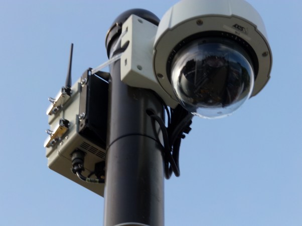 Wireless IP cameras like these allow police to set up ad-hoc surveillance networks without a need for any existing infrastructure. You can see the cameras and routers are recently attached with pipe strap. Photos by Kenneth Lipp.