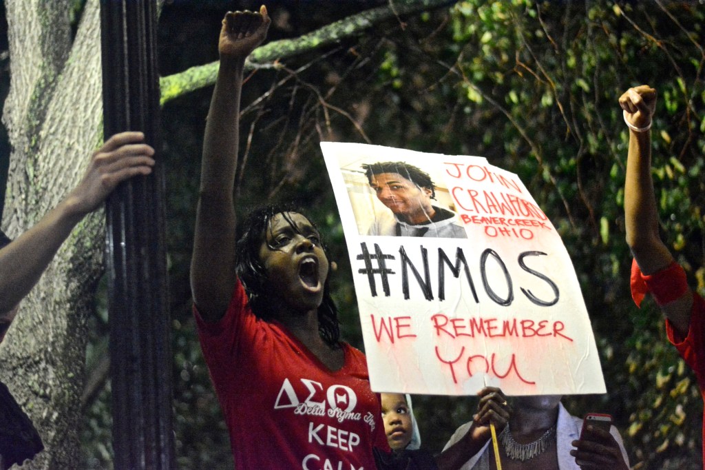 Woman holds fist in the air while leading crowd in chant. ( Photo By Joshua Albert)