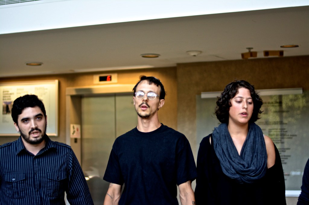 Three of six Jewish Voices for Peace activists hold hands while occupying the Jewish Community Services lobby. (Photo: Joshua Albert)