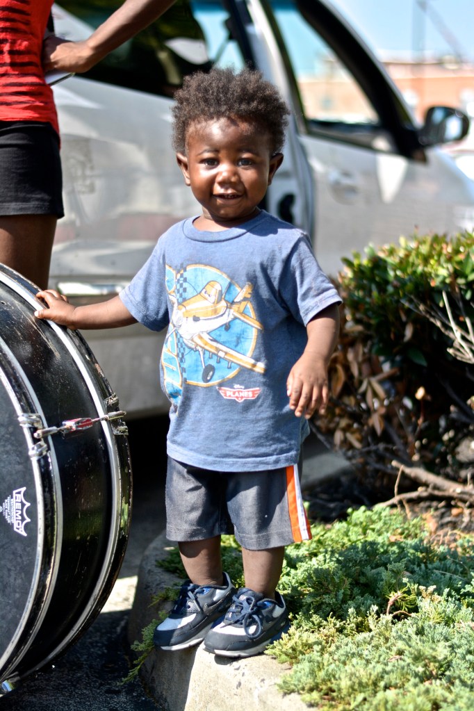 A young child arrives with drum line. 
