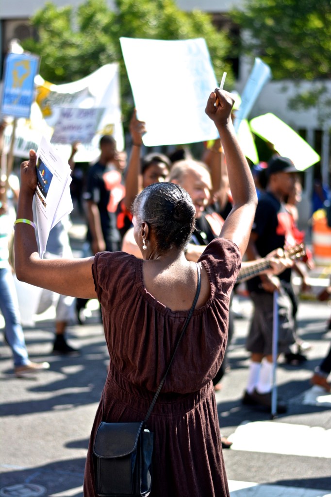 A bystander cheers on protesters. 